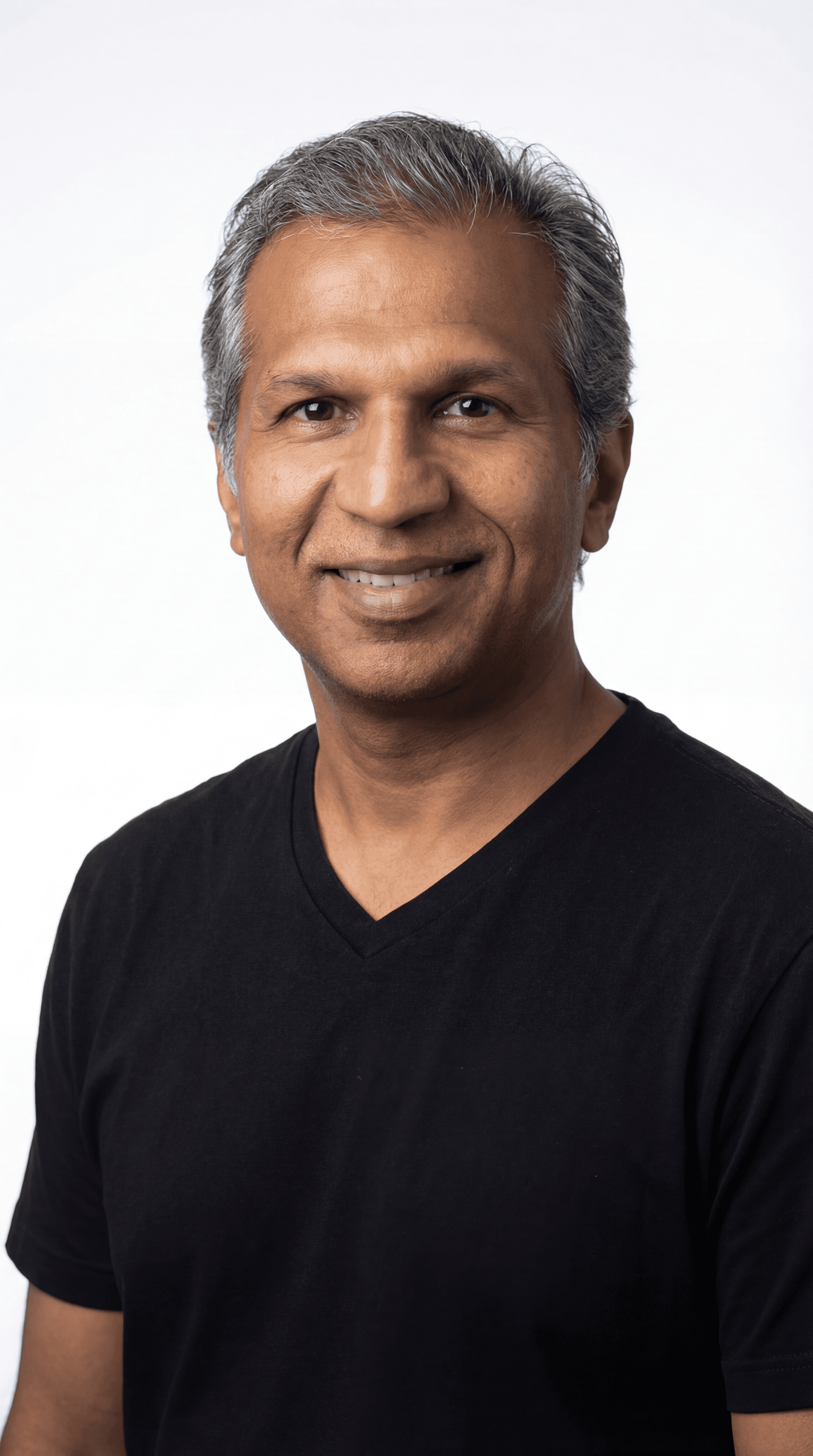 Smiling middle-aged man with salt-and-pepper hair wearing a black v-neck t-shirt against white background.